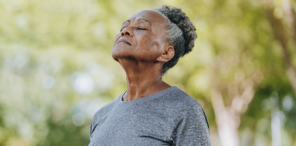 Senior woman breathing fresh air in nature